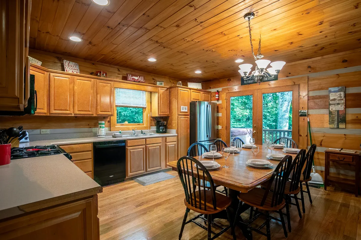 A bright dining and kitchen area with a dining table near large windows, a kitchen counter, and a view outdoors. The space feels inviting, ideal for entertaining, cooking, and enjoying scenic views during meals or games.