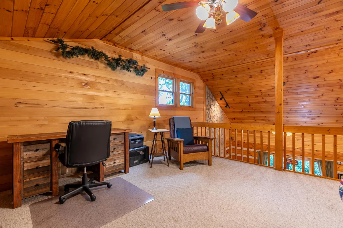 A tranquil and functional study nook featuring a wooden desk, ergonomic office chair, blue armchair, and soft lighting. The space invites productivity and relaxation, ideal for reading, working, or enjoying a quiet moment away from group activities.