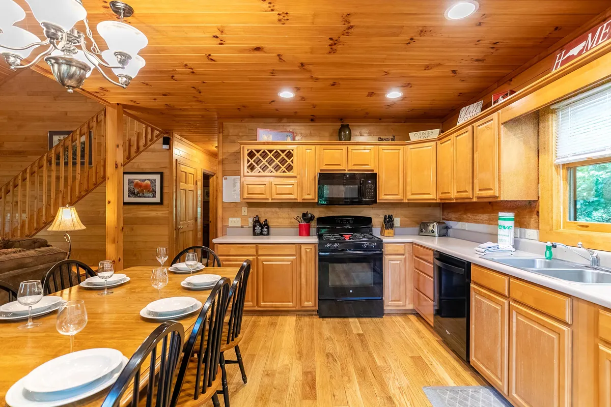 Close-up of the kitchen and dining area, highlighting a large dining table, ample kitchen countertops, and a modern stove—perfect for preparing and sharing meals. The cabinetry and layout suggest both functionality and warmth, in line with family gatherings and special occasions.