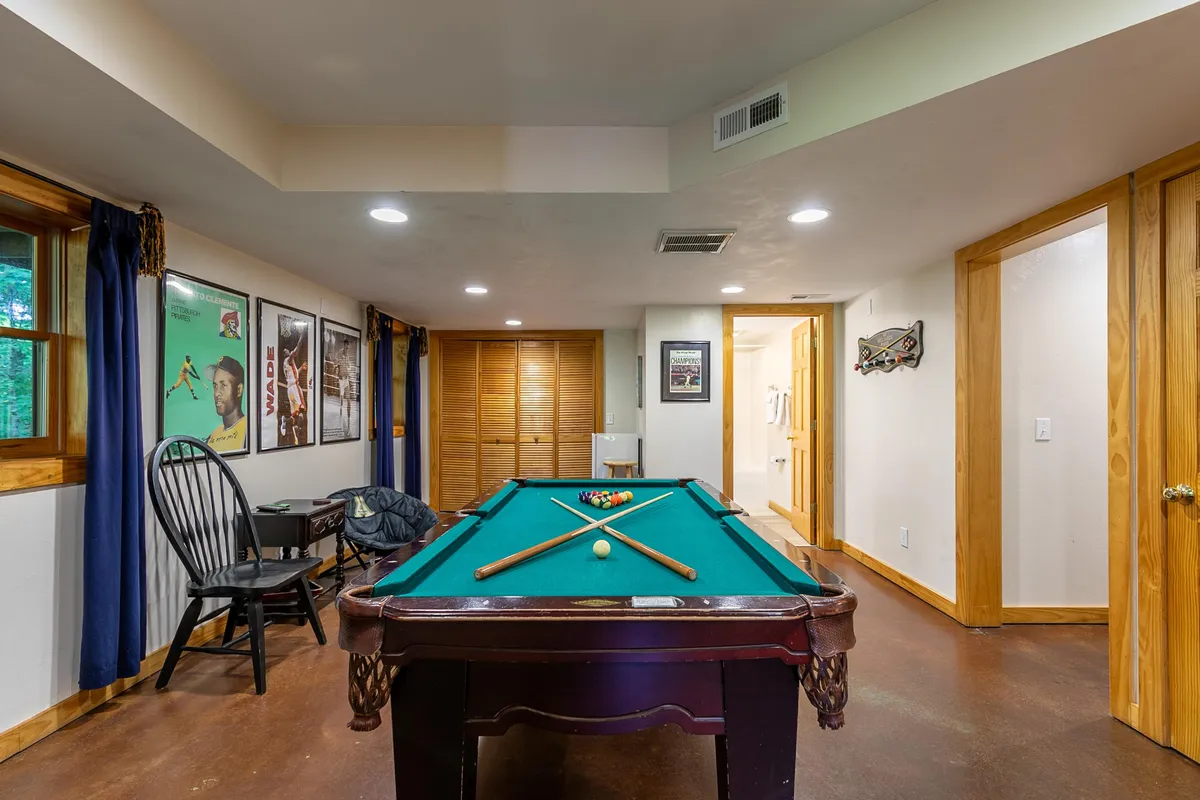 An inviting interior game area with a pool table, framed posters, and a wooden chair. The space is bright and casual, ideal for friendly competition and group gatherings.