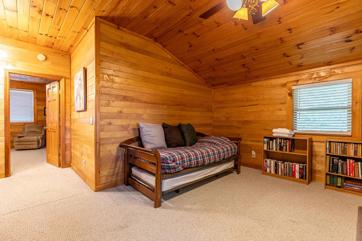 A cozy loft area with a daybed, wooden walls, and a bookshelf. This intimate space is perfect for reading, relaxing, or socializing, embodying a playful and flexible hideaway atmosphere.